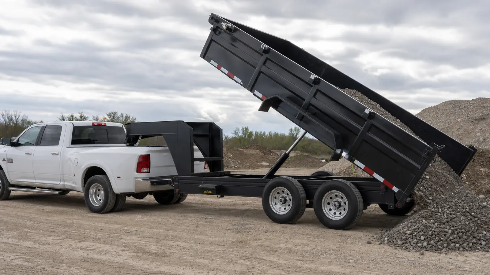 Gooseneck dump trailer unloading gravel with its hydraulic bed raised Gooseneck dump trailer unloading gravel with its hydraulic bed raised