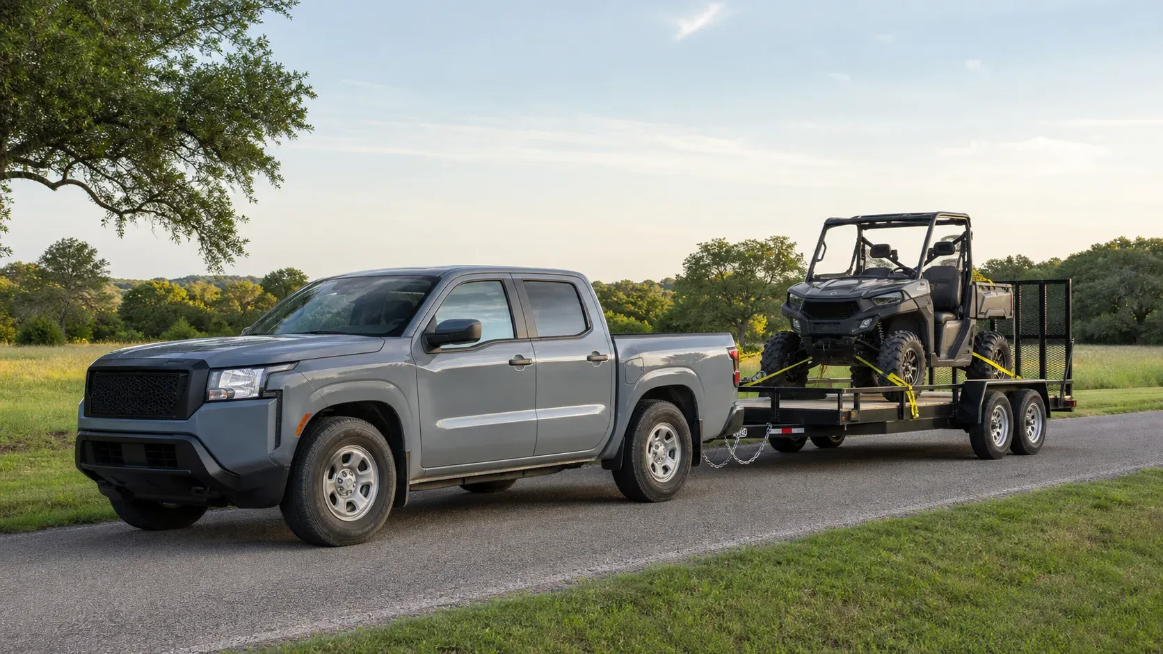 Mid-size crew-cab pickup towing a utility trailer with a secured side-by-side