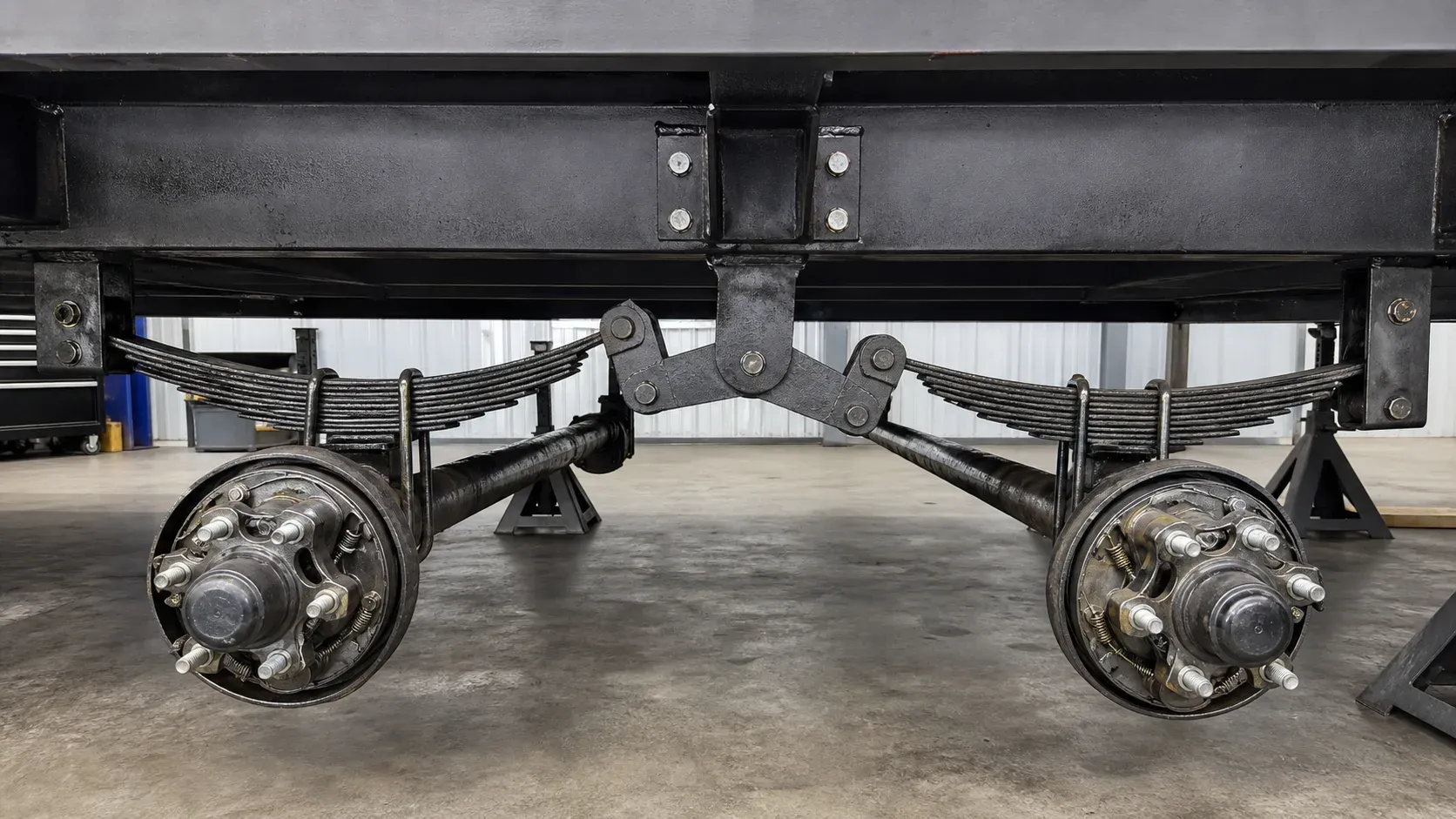 Tandem leaf springs connected through a central load-sharing equalizer