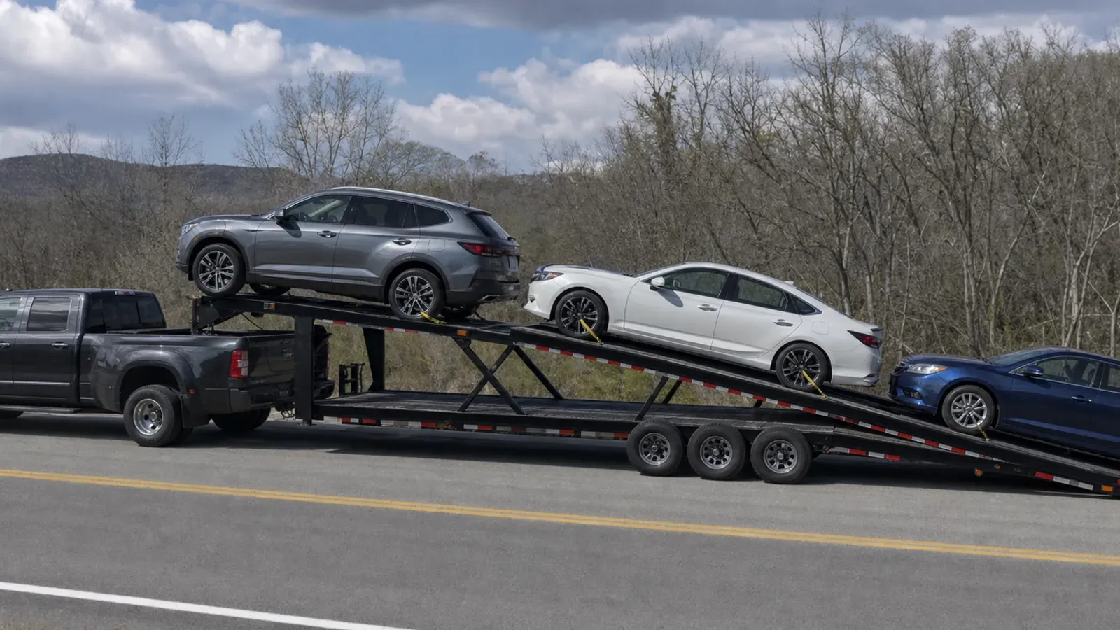 Three passenger vehicles secured on a gooseneck wedge car hauler Three passenger vehicles secured on a gooseneck wedge car hauler